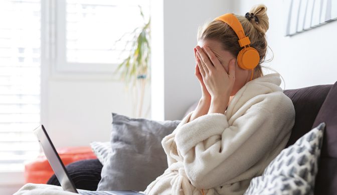 Stressed business woman in her casual home bathrobe working remotly from her living room during corona virus pandemic crisis. Stay at home and social distancing