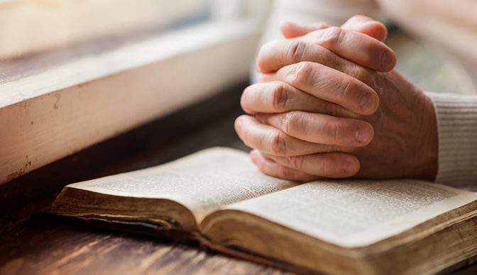 Raamattu ja rukoilevat kädet
